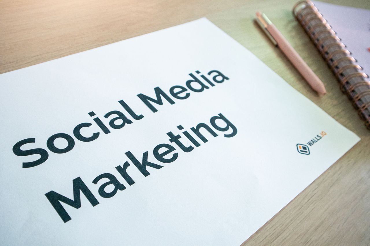 A close-up view of a social media marketing document lying on a desk beside a pen and notebook.